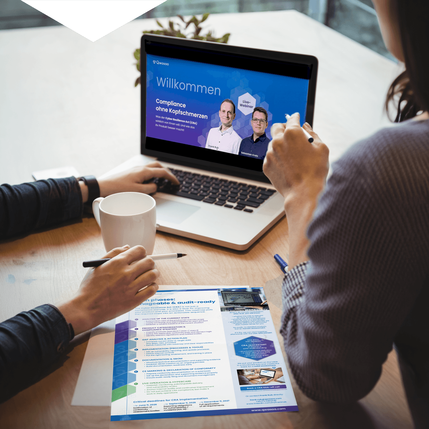Two people are viewing a Qwasaa webinar on CRA compliance on a laptop, with Qwasaa’s CRA roadmap laid out in front of them.